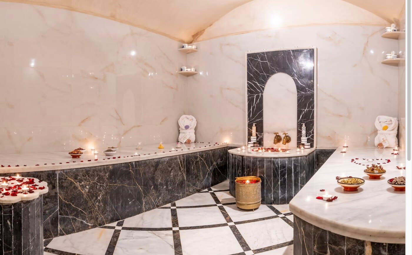 Intérieur voûté du hammam marocain du Riad Hamdane, marbre noir et blanc, bougies et pétales de rose