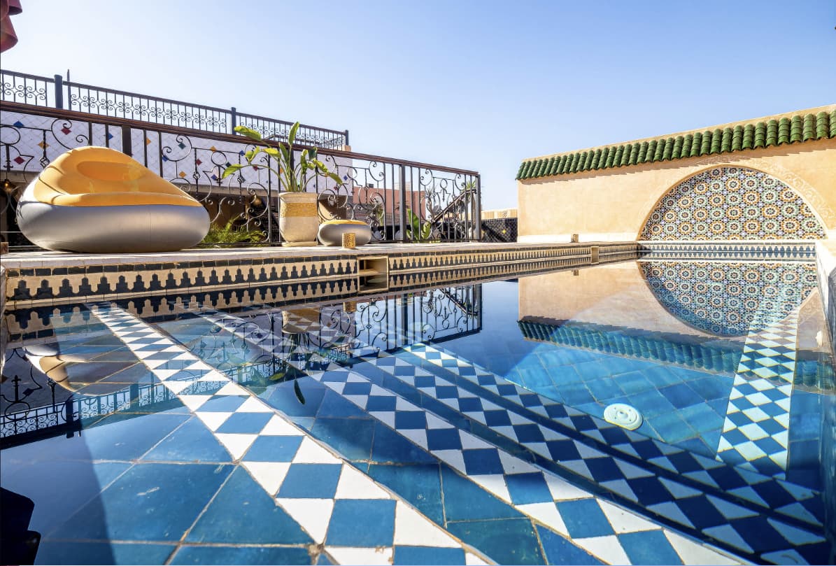 Piscine en zellige bleu et blanc sur le rooftop du Riad Hamdane, toits en tuiles vertes de Fès